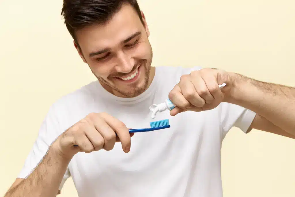 attractive young bearded man is brushing his teeth