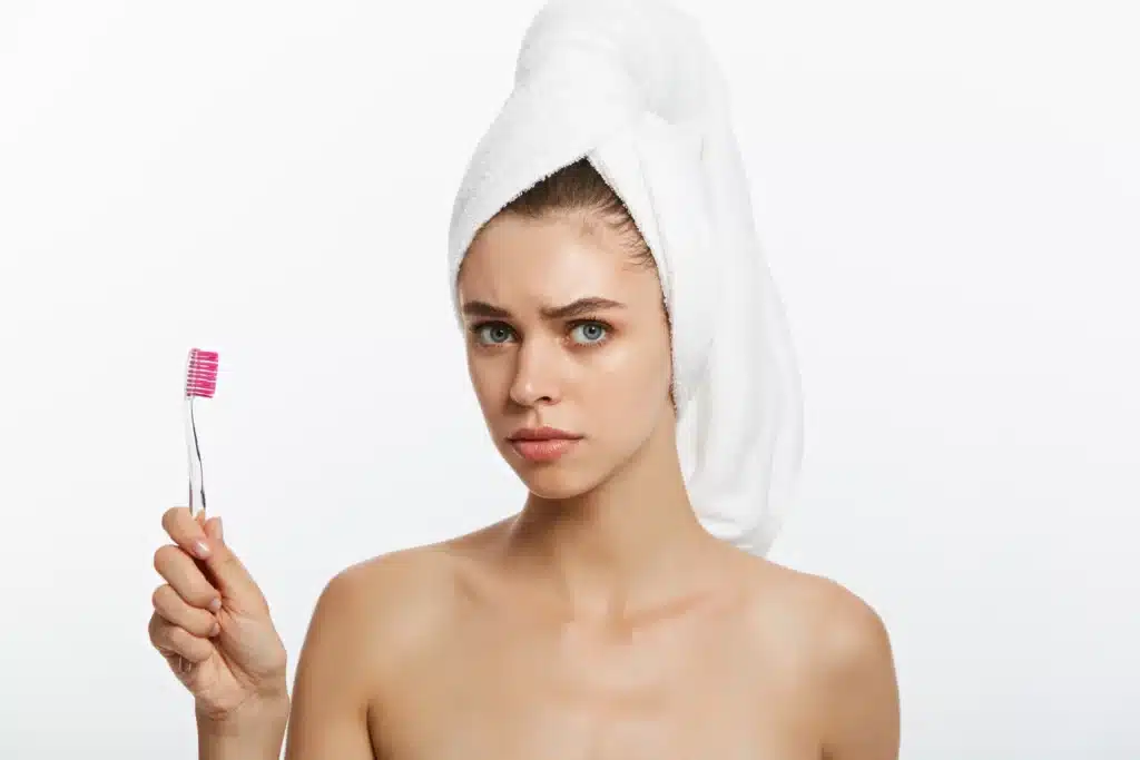 smiling woman brushing her teeth with towel on her head a great smile